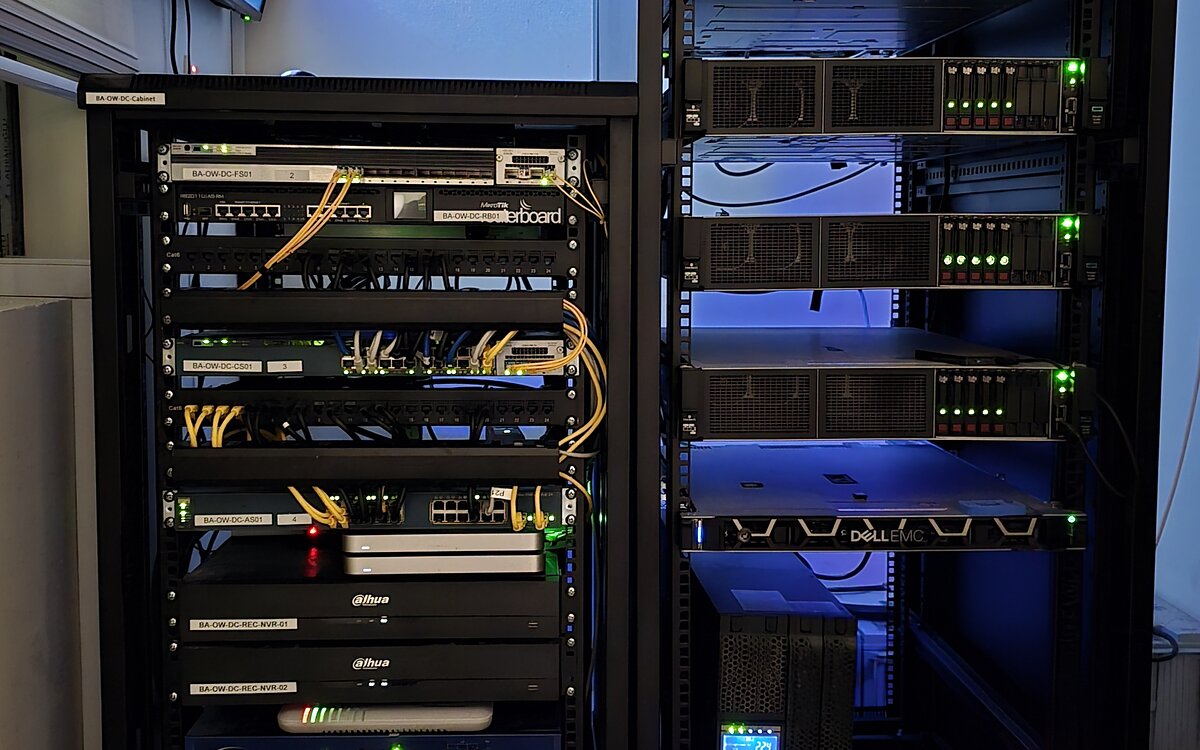 Two floor-standing equipment cabinets at Caesar Pack / Balad Al-Khair — one holding patch panels, network switches and rack-mounted recorders, the other rack servers, storage and a UPS