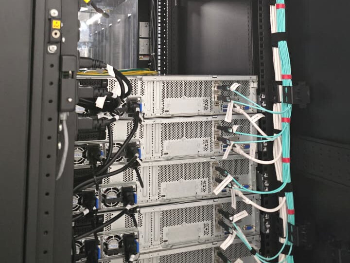 Rack-mounted servers with aqua fibre and power cabling routed down the cabinet's vertical cable channel