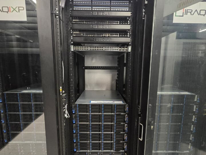 Open rack cabinet with network switches above a column of rack-mounted servers, seen between glazed cabinet doors