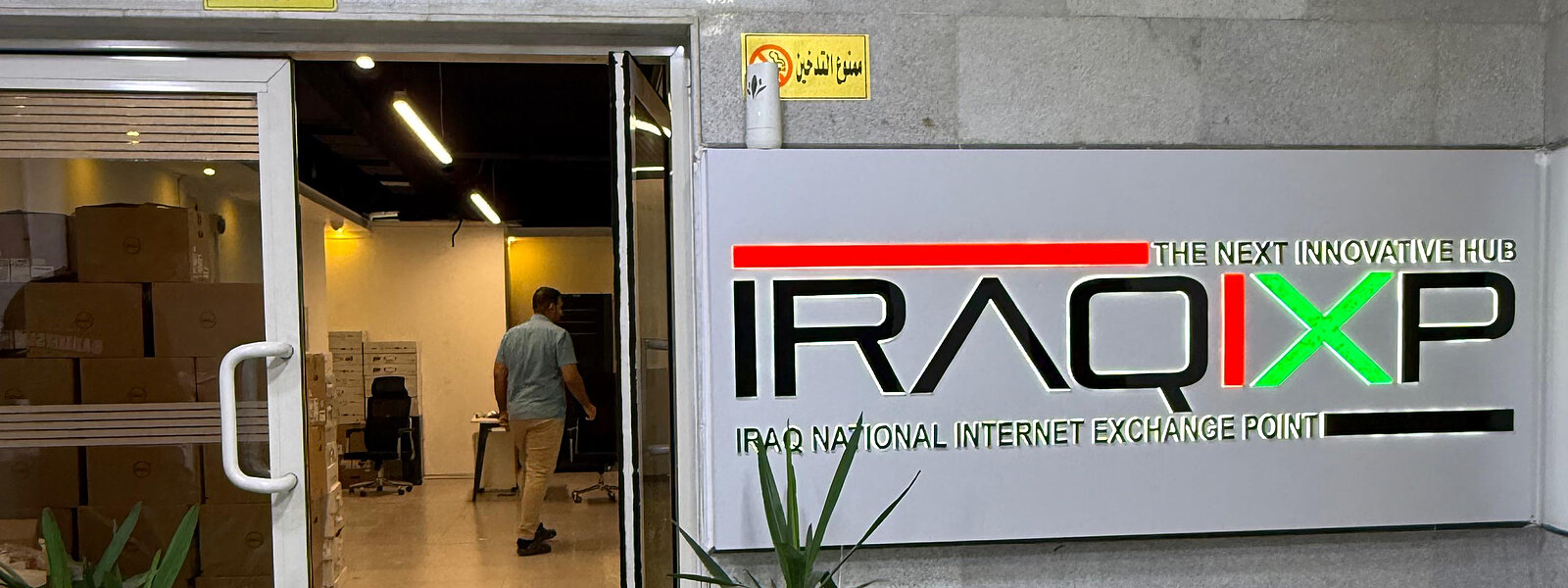 Entrance to the Iraq IXP facility, with wall signage reading IRAQIXP — Iraq National Internet Exchange Point beside the glazed doorway